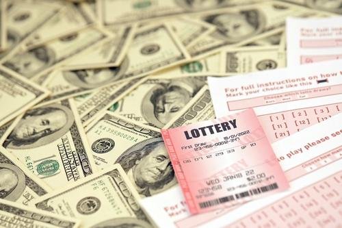 A pile of money and lottery tickets
Description automatically generated